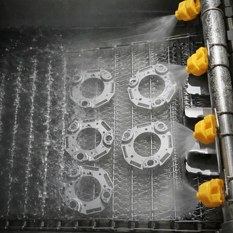 Metal-parts-being-cleaned-by-high-pressure-spray-nozzles-in-an-industrial-washing-system.jpg